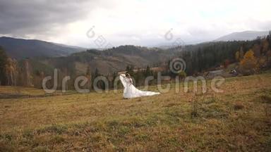 华丽欢快的新娘正沿着奇妙的草地奔跑。 美丽的大自然笼罩着金色的山脉。